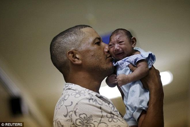 Women of child bearing age are being warned to consider trips to Brazil 'carefully' ahead of the Olympic Games this August. Pictured: Geovane Silva holds his son Gustavo Henrique, who has microcephaly - one of more than  4,000 babies to be born with the condition in the last 12 months © Reuters