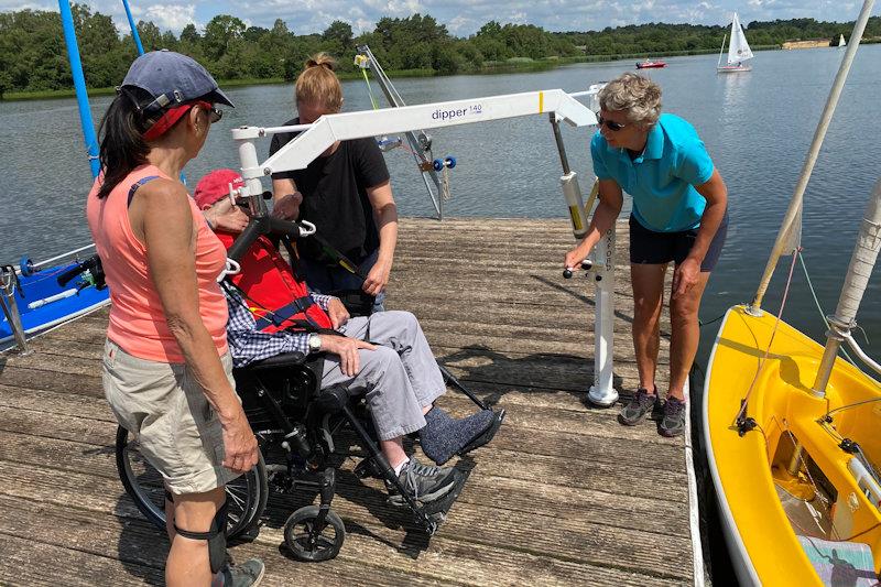 Hoist process step 2 - check the sailor is ready before pumping on the handle to raise them up (the sling will gradually tighten around them and could be painful if not in the right place) photo copyright Magnus Smith taken at Frensham Pond Sailability and featuring the Hansa class