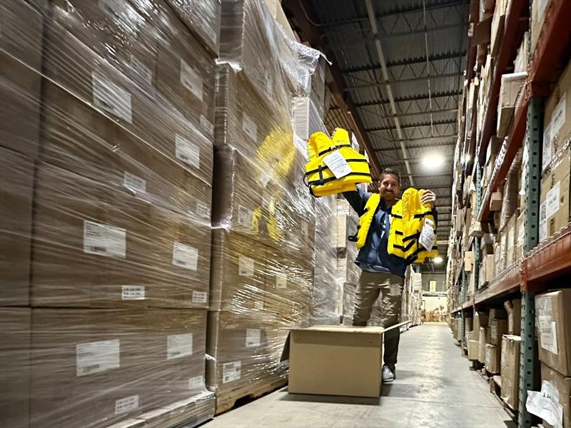 Ray Fernandez shows off life jackets and mountains of boxes from the grant shipment  - photo © Sea Tow Foundation