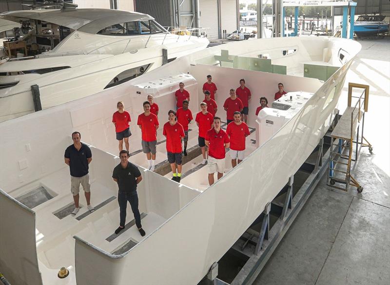 Riviera's Kyle Davison (left) and Adam Houlahan with some of the apprentices from the composite team as they stand proudly in the newly completed hull of a 72 Sports Motor Yacht before it moves on to the engineering division. - photo © Riviera Studio